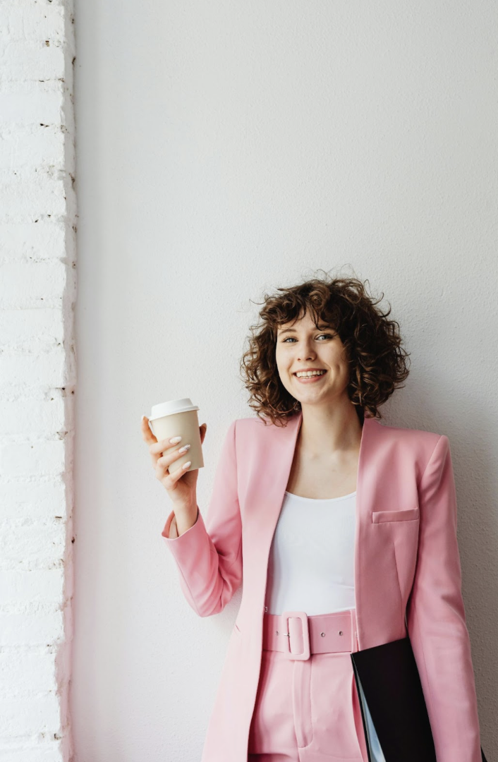 Realtor mom in pink suit holding coffee during realtor branding photoshoot